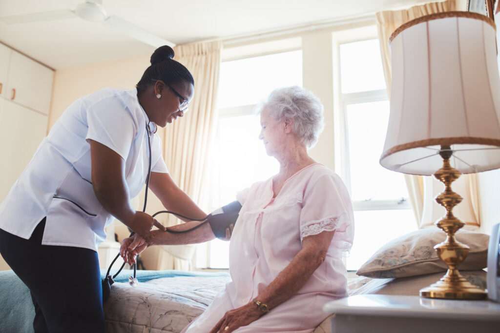 Female nurse doing blood pressure measurement of a senior woman patient. Doctor checking blood pressure of an elderly woman at old age home.